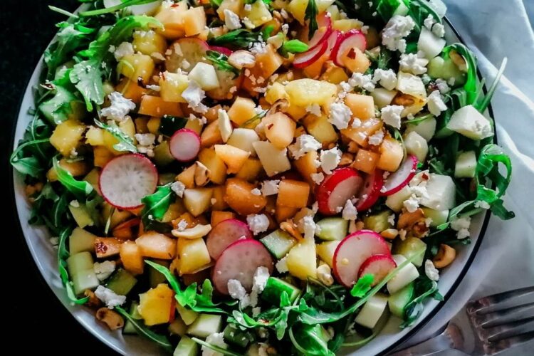 a dish of Apple, Melon And Pineapple Salad With Balsamic Vinegar and white napkin with a fork