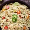 A bowl of Mexican chicken salad recipe features shredded chicken mixed with avocado, cherry tomatoes, jalapeño slices, and lime, served on a wooden table.