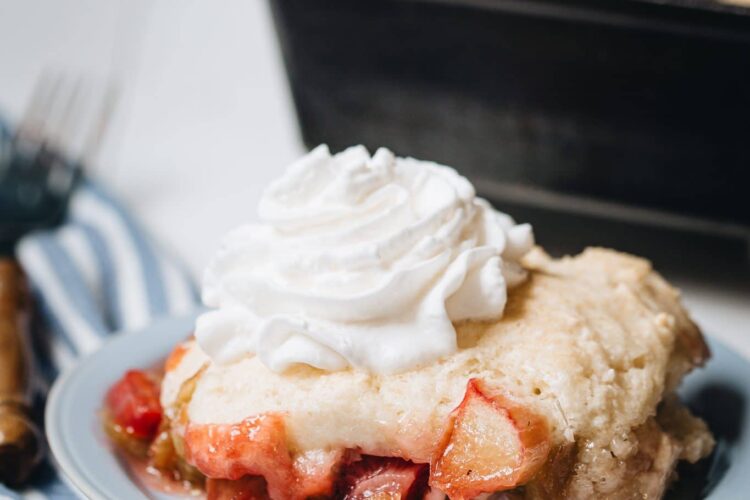 Side image of rhubarb cobbler on a plate with a cast iron baking dish in the background.