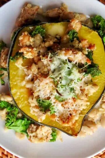 Acorn squash stuffed with kale, white beans, and cheese on a white plate, placed on a woven mat.
