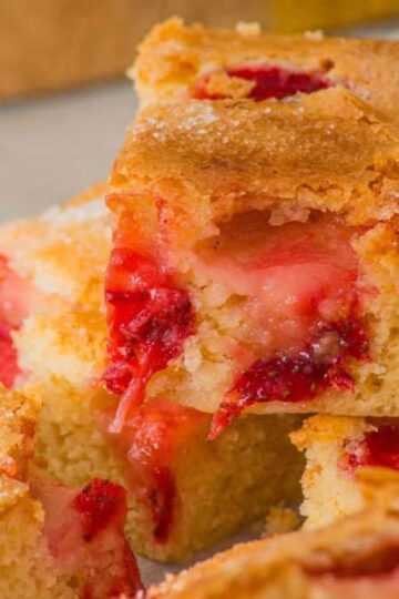 Close-up of strawberry sheet cake slices, showcasing a golden brown crust and vibrant chunks of strawberries.