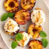 grilled peaches with scoops of ice cream on top and mint leaves for garnish on a white oval serving plate.