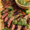 Easy grilled skirt steak is sliced with chimmichurri sauce on top for serving