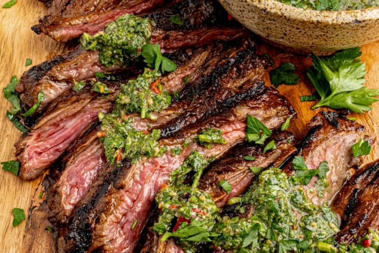 Easy grilled skirt steak is sliced with chimmichurri sauce on top for serving
