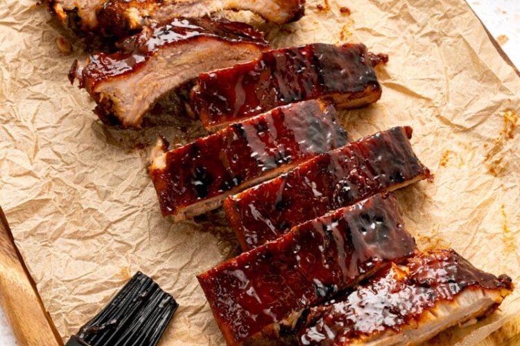 Cut oven baked ribs on a piece of parchment paper after baking in the oven.