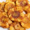 Tostones (fried green plantains) piled on a white plate for serving.