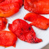 Roasted red peppers arranged on a white plate.