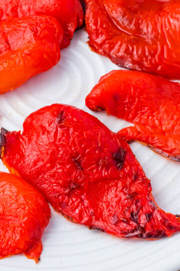 Roasted red peppers arranged on a white plate.