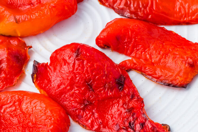 Roasted red peppers arranged on a white plate.