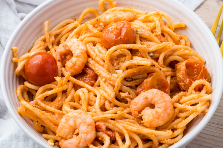 A bowl of shrimp feta pasta placed on a light-colored cloth.